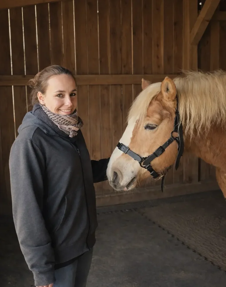 Sattlerin bei der Anpassung eines Halfters am Pferd im Stall